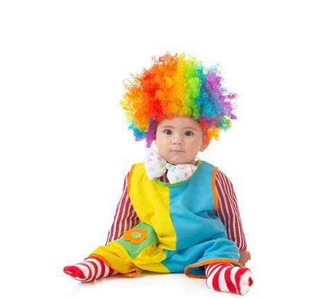 Bebé disfrazado de payaso de circo sonriendo en un fondo colorido.