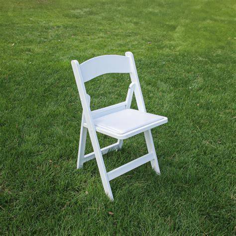 Foto de silla de ceremonia americana blanca plegable con cojín suave en un entorno de banquete al aire libre
