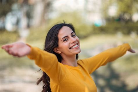 Foto de una matrona sonriendo y de brazos abiertos, en un entorno cálido.