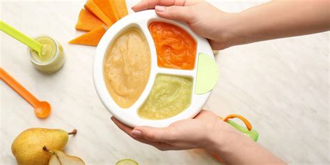 Bebé sonriendo mientras come una papilla de verduras, con un plato de colores brillantes