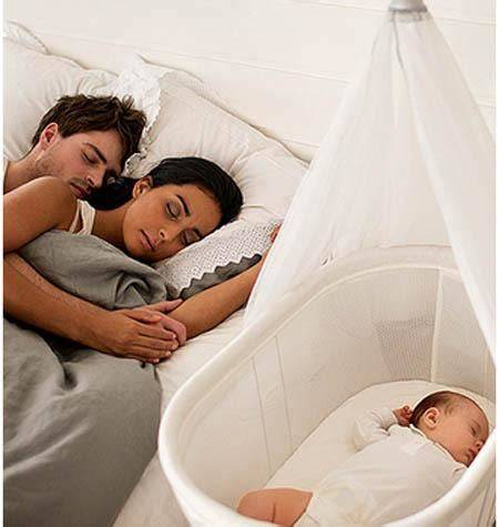 Bebé durmiendo plácidamente en una minicuna junto a los padres
