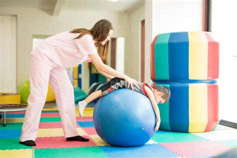 Foto temática de un niño recibiendo fisioterapia con el apoyo de un profesional.