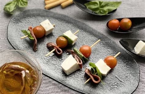 Ingredientes frescos para brochetas: tomates cherry, queso fresco, anchoas en aceite de oliva.