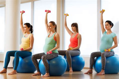 Mujer embarazada realizando ejercicios suaves en clase de gimnasia preparto