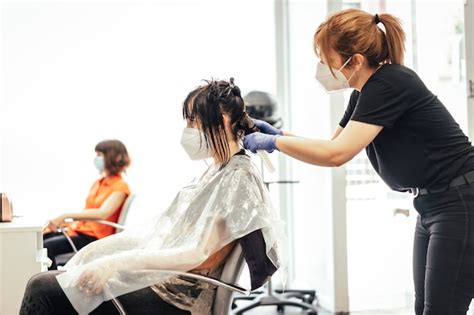 Imagen de un salón de peluquería preparado para la reapertura, con señalización de distanciamiento social y mamparas.