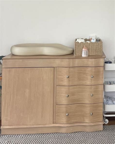 Cambiador de madera de pino con dos estantes, resaltando su material y diseño.