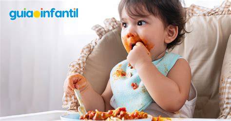 Imagen de un bebé comenzando a comer alimentos sólidos como parte de la alimentación complementaria.