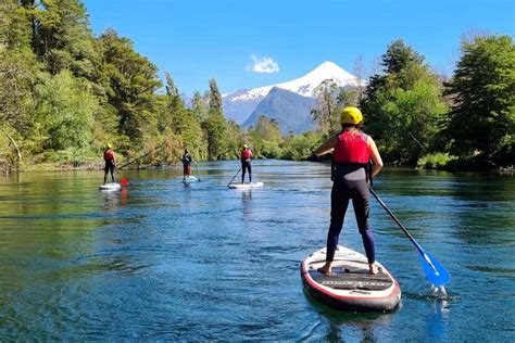 Persona haciendo paddle surf en un lago tranquilo con montañas de fondo