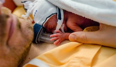 Foto temática de interacción cariñosa entre padres y bebé prematuro en un entorno de UCIN