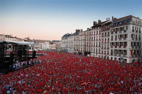 Foto panorámica de las Fêtes de Bayonne con gente vestida de rojo y blanco en las calles