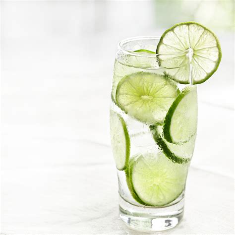 Imagen de un vaso de agua con limón y frutas frescas