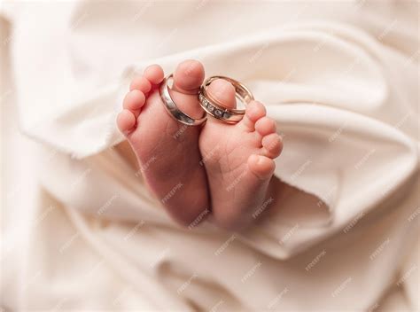 los pies de un bebé recién nacido sosteniendo dos anillos de boda