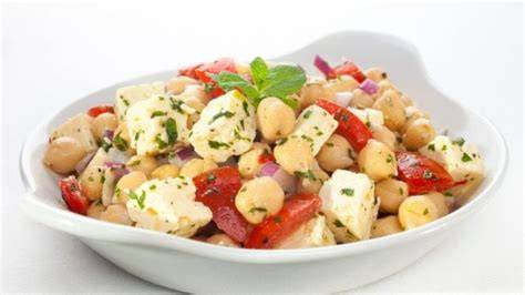 Foto de una ensalada de garbanzos, queso feta y pimientos recién preparada en un bol