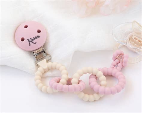 Sujetachupetes de silicona de varios colores con clip y cinta para el chupete.