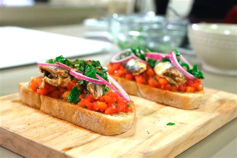foto de un aperitivo de tostadas integrales con sardinas, cebolla roja y perejil