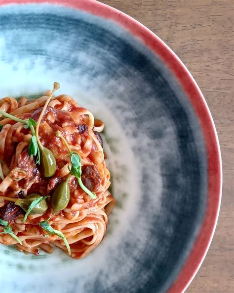 Sándwich con tomate picado, anchoas, alcaparras y cebolla roja.
