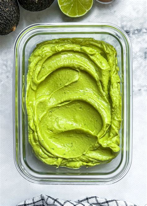 Primer plano de un sándwich abierto mostrando el untable de aguacate y queso feta sobre pan.