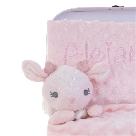 Detalle de una canastilla personalizada con el nombre del bebé bordado en un babero y un peluche.