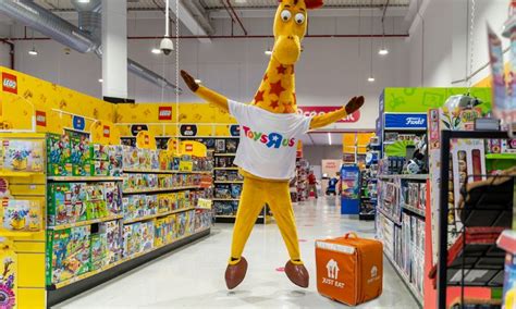 Interior de una tienda Toys R Us con una amplia sección de puericultura y minicunas