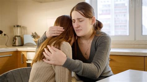 Una madre consolando a su hijo/a adolescente.