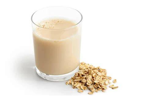 Foto de copos de avena esparcidos junto a un vaso de bebida de avena