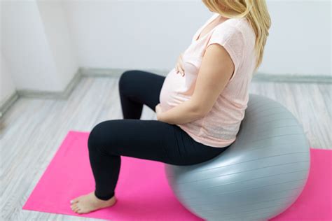 Mujer embarazada utilizando una pelota de pilates durante el parto para aliviar el dolor