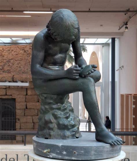 Escultura clásica del Niño de la Espina (Spinario) en un museo