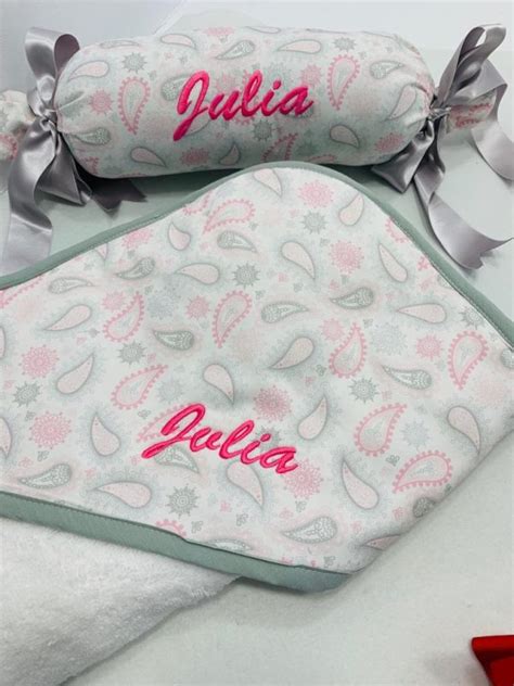 Variedad de productos personalizados para bebés, incluyendo chupetes, baberos y mantas bordadas