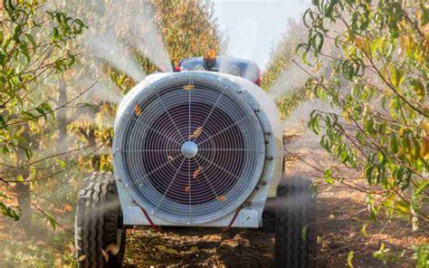 Atomizador agrícola arrastrado trabajando en un campo de viñedos