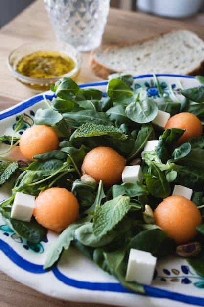 Foto de melón cantalupo cortado en bolitas, mezclado con queso feta y hojas verdes