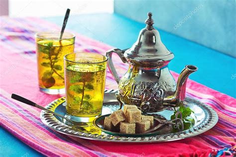 Fotografía de una mesa festiva marroquí con diversos dulces tradicionales y té a la menta.