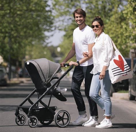 Foto de una silla de paseo moderna en uso, con el bebé y los padres disfrutando de un paseo