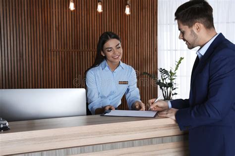 Oficina de recepción de un hotel con recepcionista atendiendo a un cliente