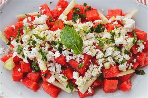 Fotografía cenital de una ensalada fresca con gambas, dados de queso feta, sandía y hojas de menta para un contraste de colores vibrantes.