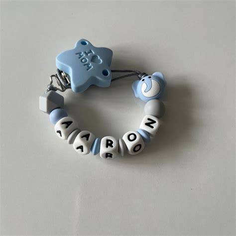 Chupetero gris plata y azul o rosa personalizado con el nombre del bebé, con chupete de estrellas grises.