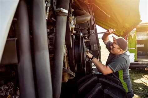 Trabajador agrícola realizando mantenimiento preventivo a un tractor