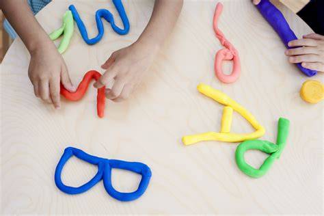 Niños jugando con letras de plastilina y materiales reciclados