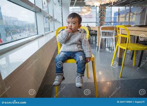 Niño sentado en una silla de peluquería con forma de coche de bomberos rojo, sonriendo
