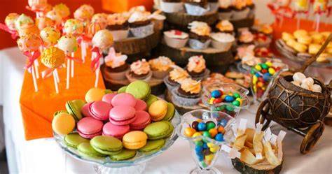 Imagen de una mesa de fiesta infantil con conos de dulces que incluyen chupetes caramelo en anillo