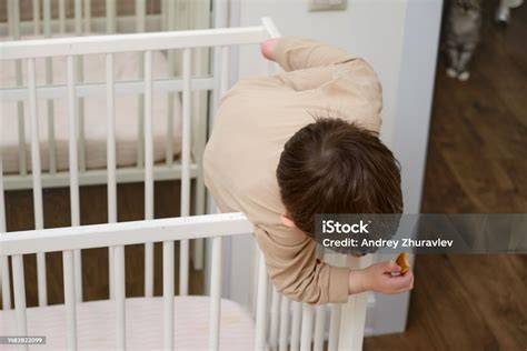 Bebé intentando trepar por los barrotes de una cuna