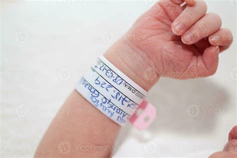 Ilustración de un bebé recién nacido con su pulsera de identificación en el tobillo, junto a la mano de su madre con la pulsera a juego.