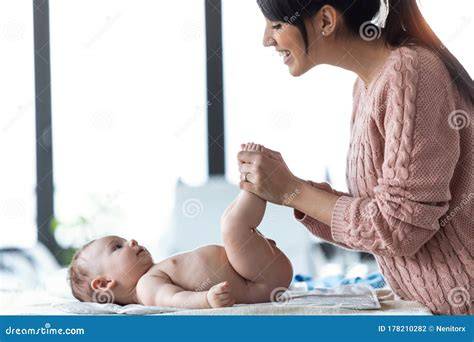 Foto de una madre sonriendo mientras cambia un pañal a su bebé