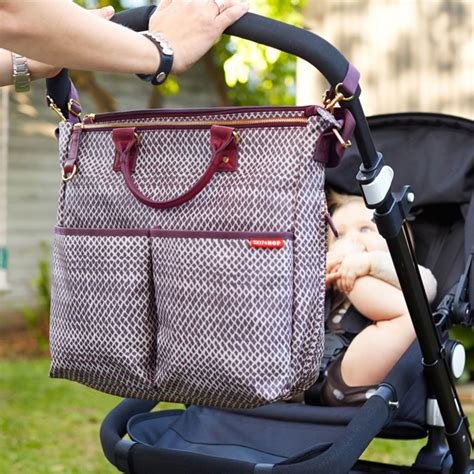 foto de un bolso cambiador Skip Hop colgado de un cochecito de bebé, mostrando su diseño moderno y funcional.