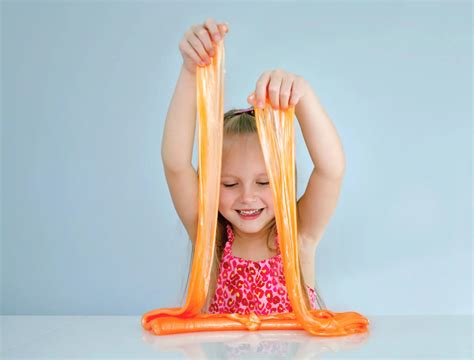 Niño jugando con un slime de purpurina azul recién hecho.