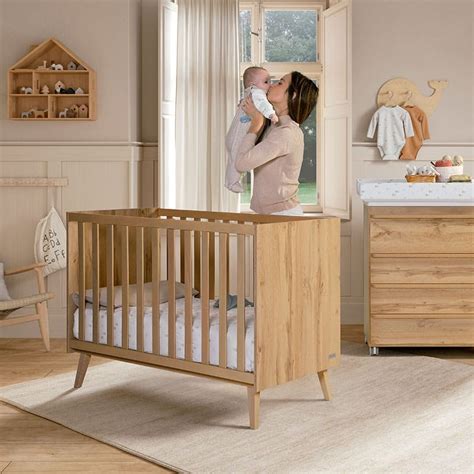 Foto temática de una cuna Micuna Nova en color miel en una habitación de bebé decorada con tonos cálidos