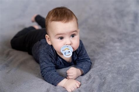 Foto de un niño colgando su chupete en un árbol, con padres ayudando