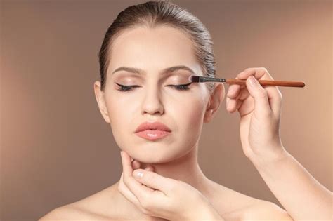 Foto de una persona aplicando maquillaje compacto en su rostro, con un rayo de sol incidiendo suavemente.