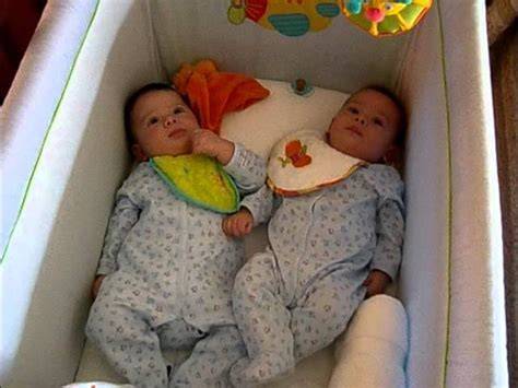 Bebés gemelos durmiendo juntos en una cuna sidecar