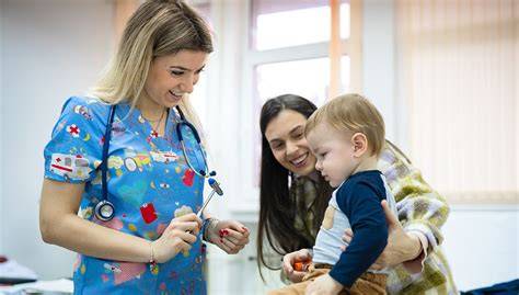 Enfermera pediátrica con uniforme interactuando de forma amigable con un niño en un área de juegos hospitalaria