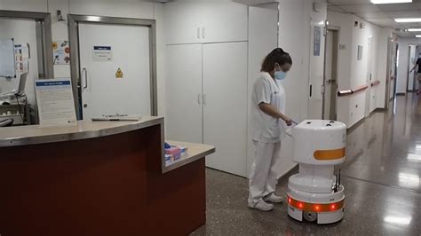 Ilustración de un robot de logística hospitalaria transportando carros en un pasillo.